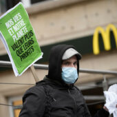 A demonstrator wearing a protective face mask during a May Day protest stands in front of a Mac Donald's restaurant