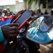 A motorbike driver looks at his GPS cashless payment device outside of Nyamirambo stadium in Kigali, Rwanda