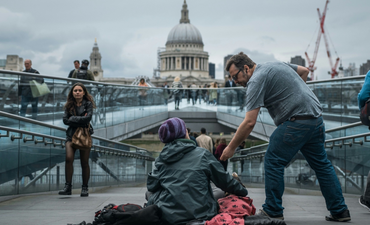 A man reaches out to a homeless person in London